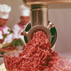 Close-up of ground beef in a glass bowl with chefs in background